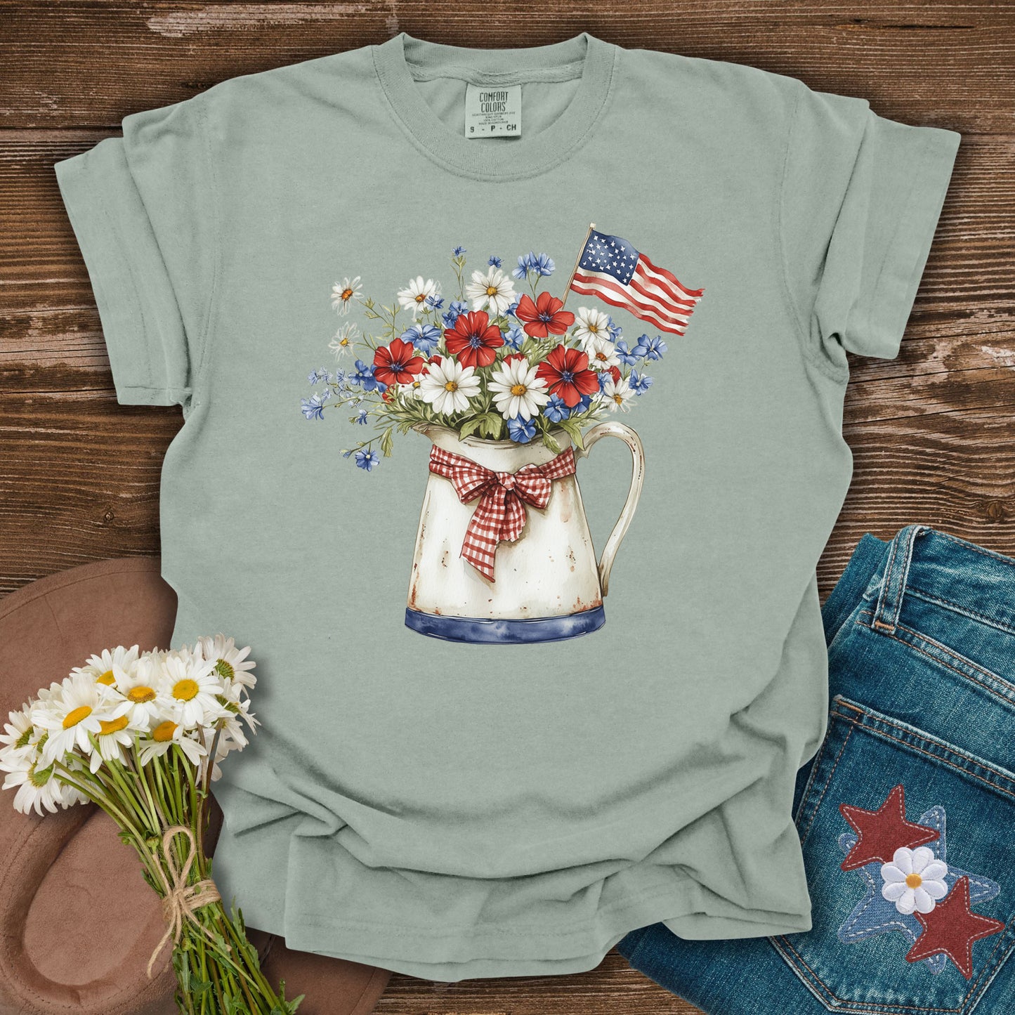 Green t-shirt with floral design and American flag on a wooden surface