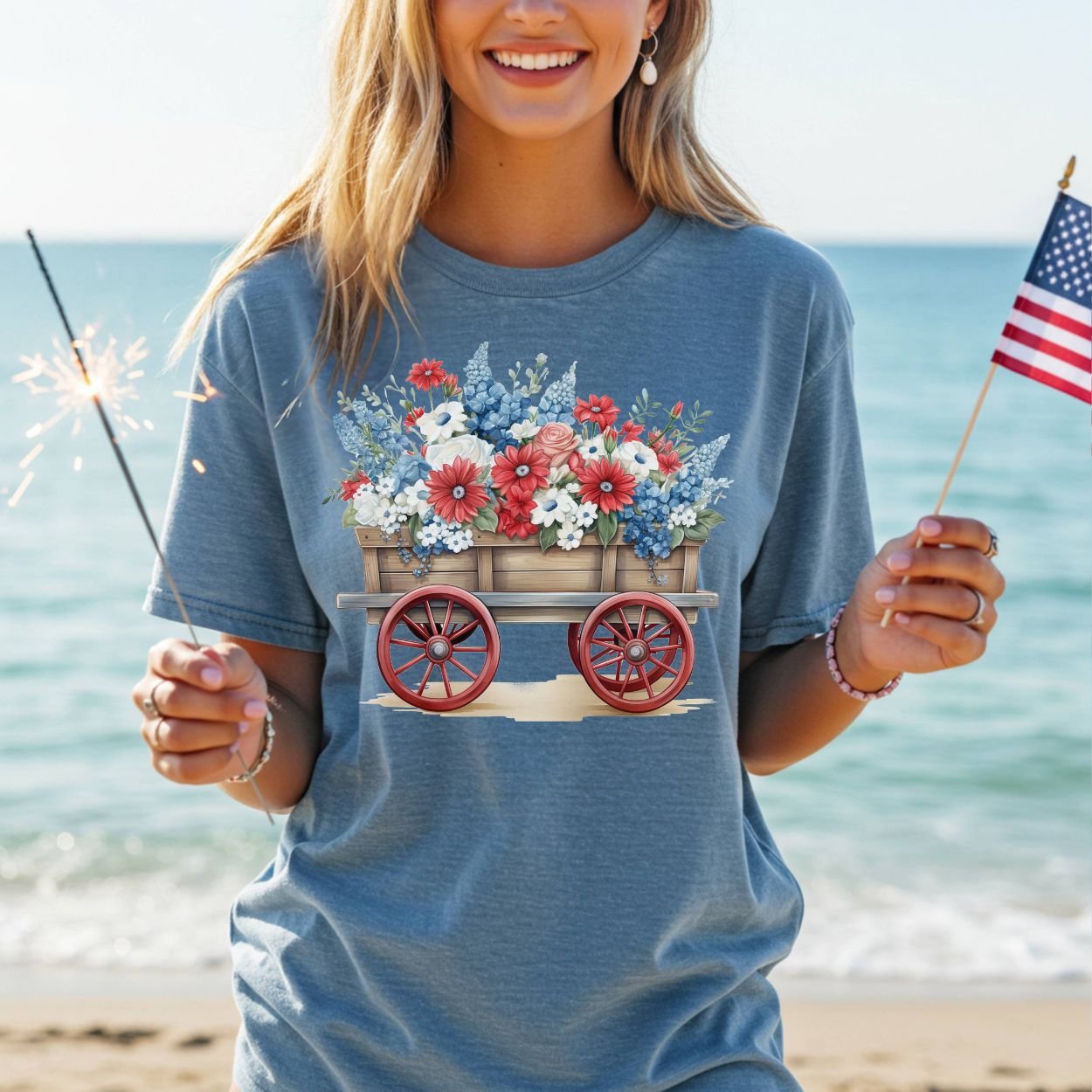 Garment-dyed blue cotton t-shirt with a patriotic flower wagon design, worn by a woman on a beach.