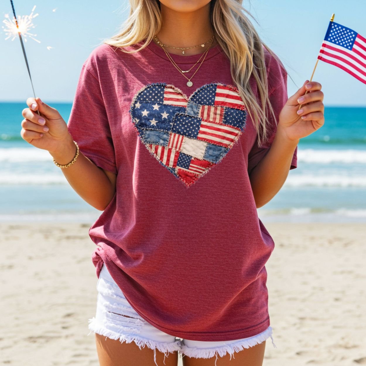 Patriotic heart faux quilt t-shirt with American flag patchwork design, worn by a person on a beach.