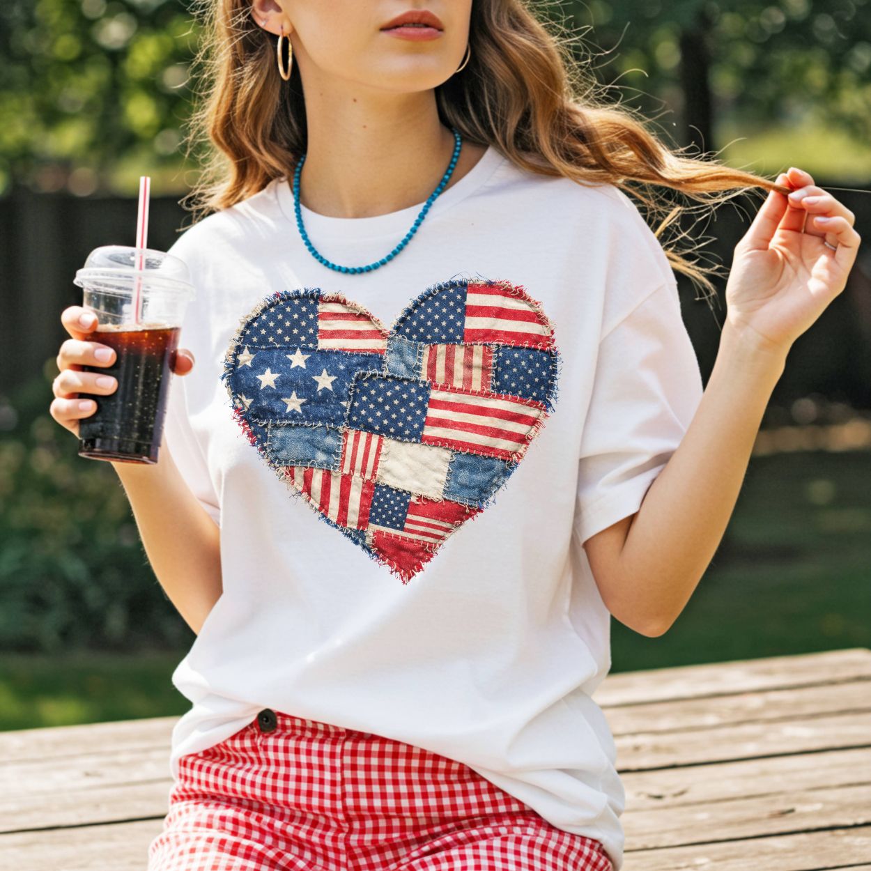 White t-shirt with a distressed faux quilt heart design made from American flag patterns.