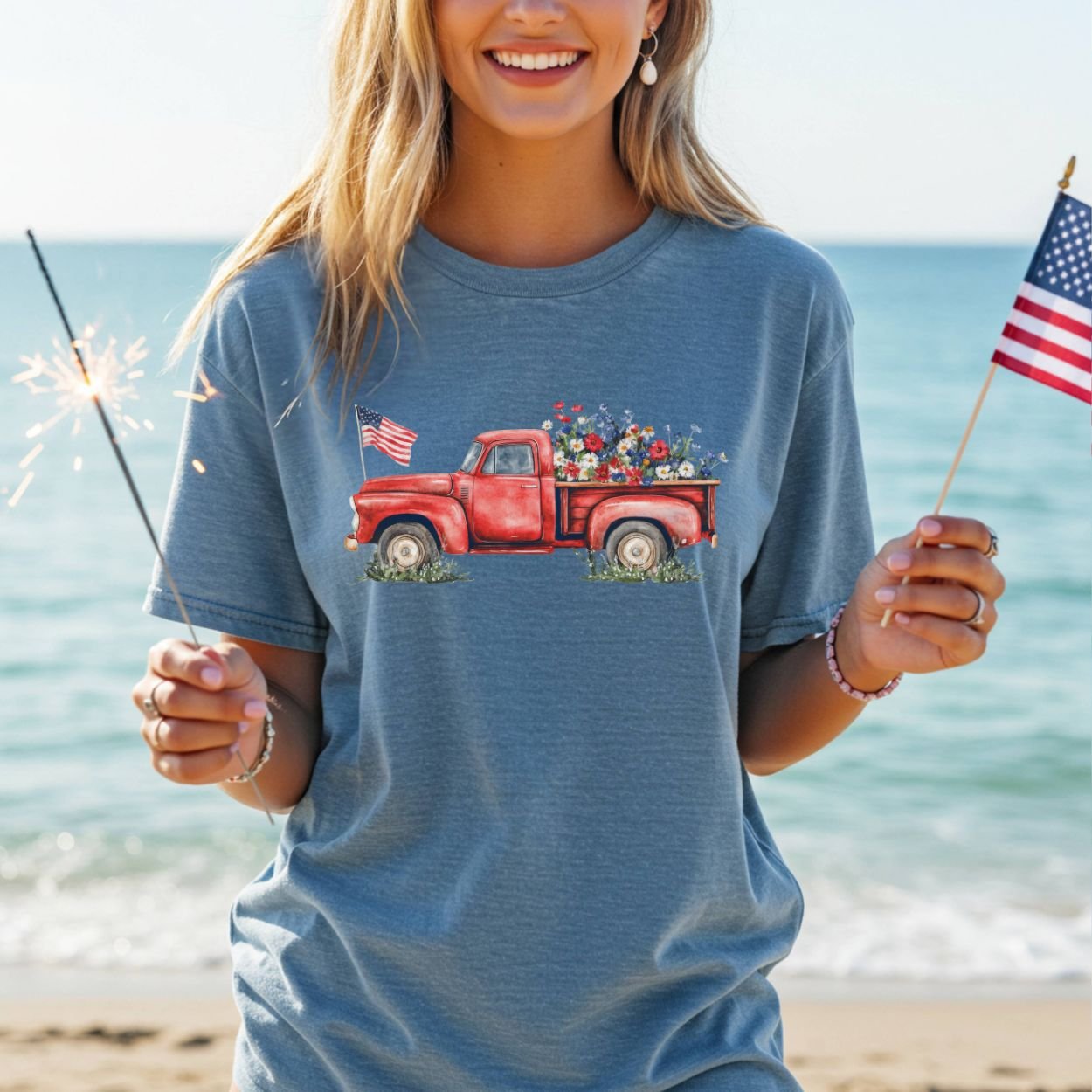 Woman in a blue garment-dyed t-shirt with a vintage red pickup truck, wildflowers, and American flags.