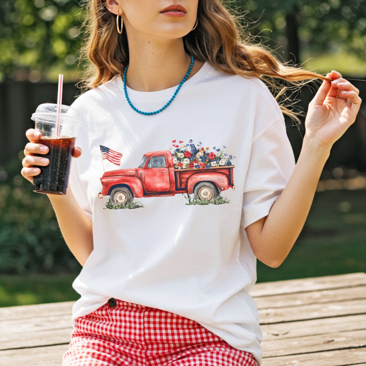 White cotton t-shirt with a watercolor red pickup truck, overflowing wildflowers, and an American flag.