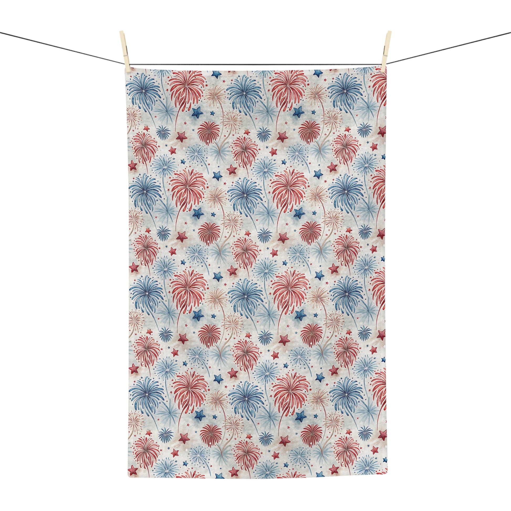 Microfiber tea towel with watercolor red, blue, and neutral fireworks and star pattern, hanging on a line.