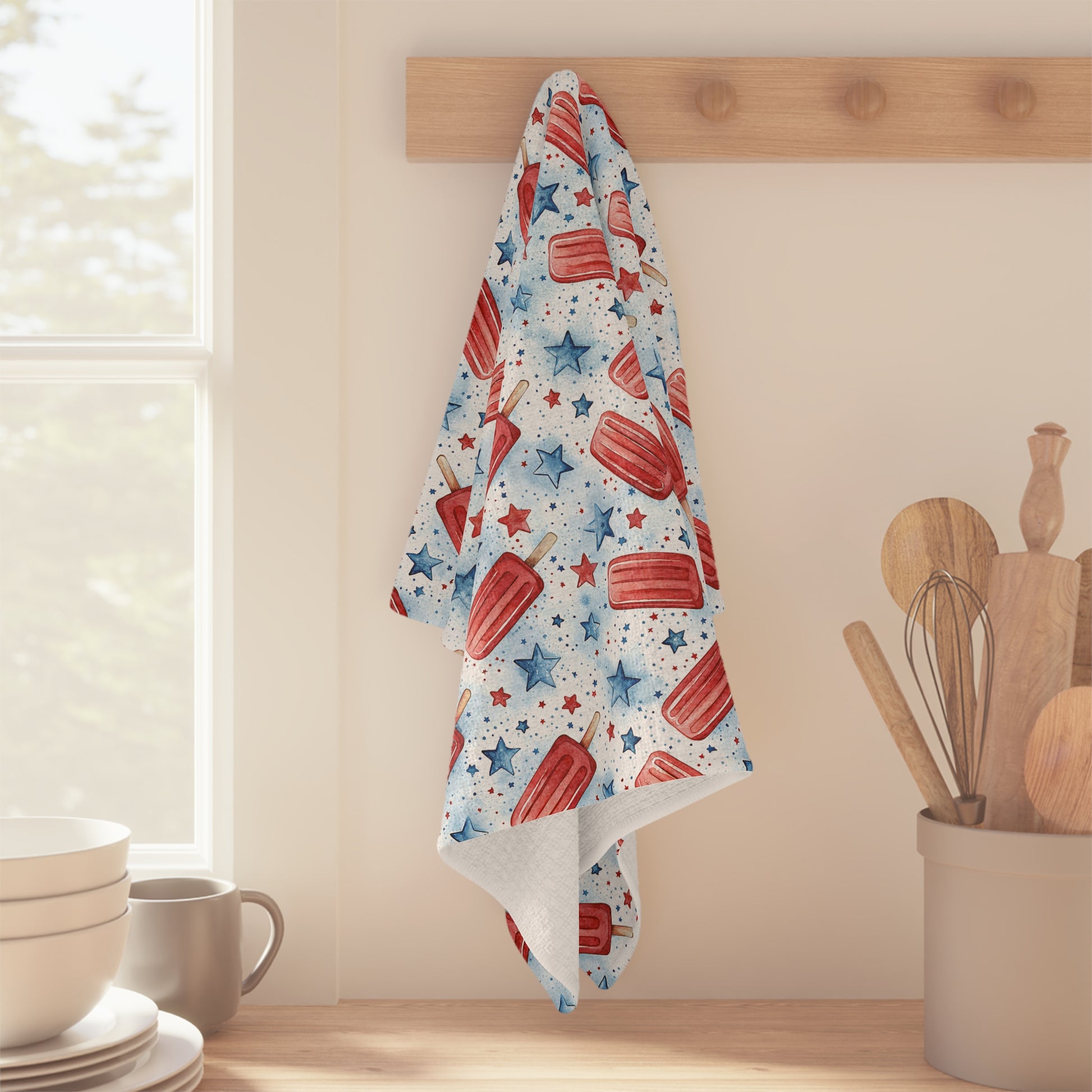 Patriotic microfiber tea towel with red popsicles and blue stars, hanging on a wooden peg.