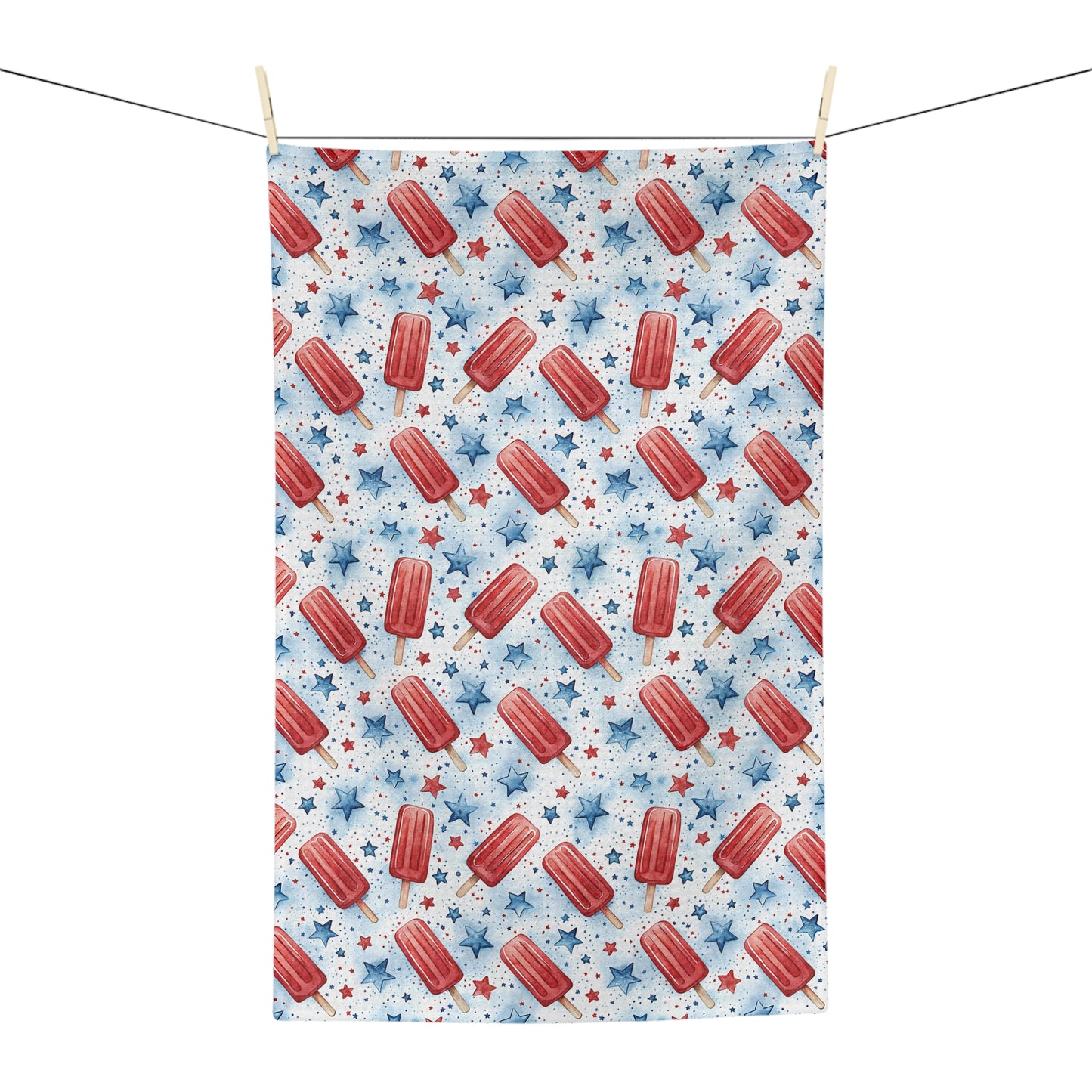 Microfiber tea towel with red popsicles and blue stars, hanging on a clothesline.