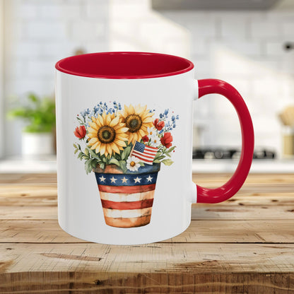 White ceramic mug with red interior and handle, featuring a patriotic sunflower, poppy, and blue blossom bouquet in an Americana-striped pot.