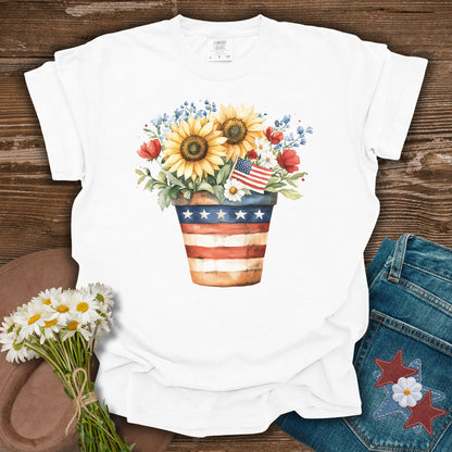 White S t-shirt with a patriotic sunflower bouquet in an American flag pot, daisies, and roses.