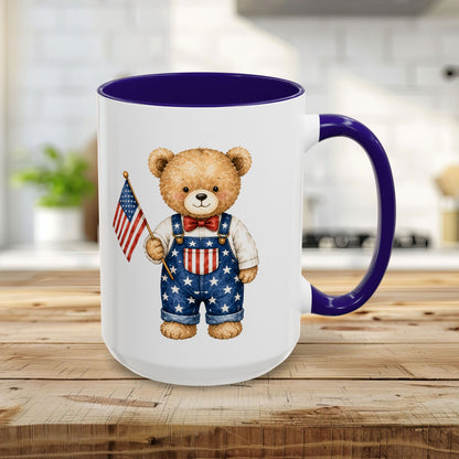 15oz ceramic mug with a watercolor teddy bear in star-spangled overalls holding a flag, blue interior and handle.