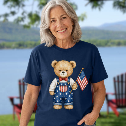 Woman in a navy blue t-shirt with a teddy bear in Americana overalls holding a US flag.