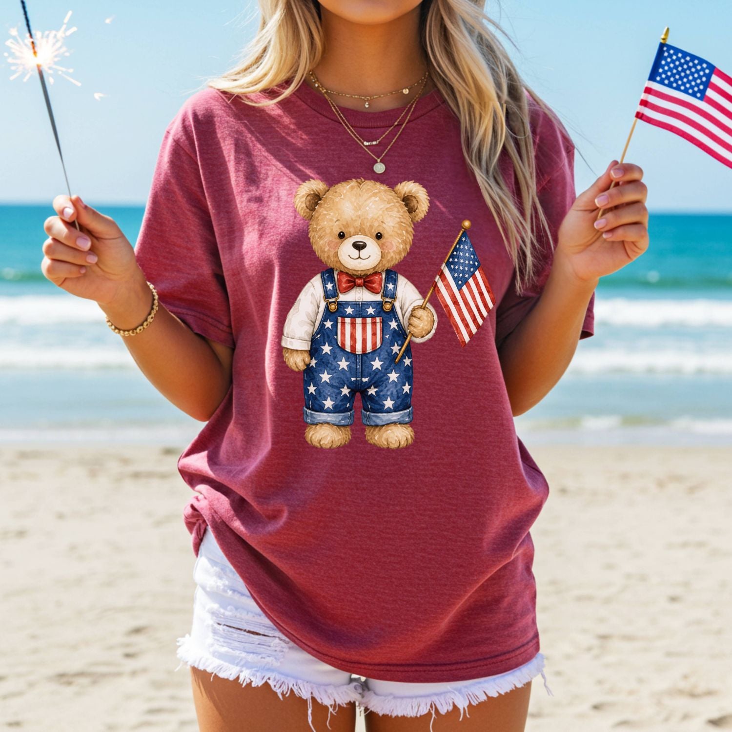Garment-dyed red t-shirt with a hand-drawn teddy bear in Americana overalls holding a flag.