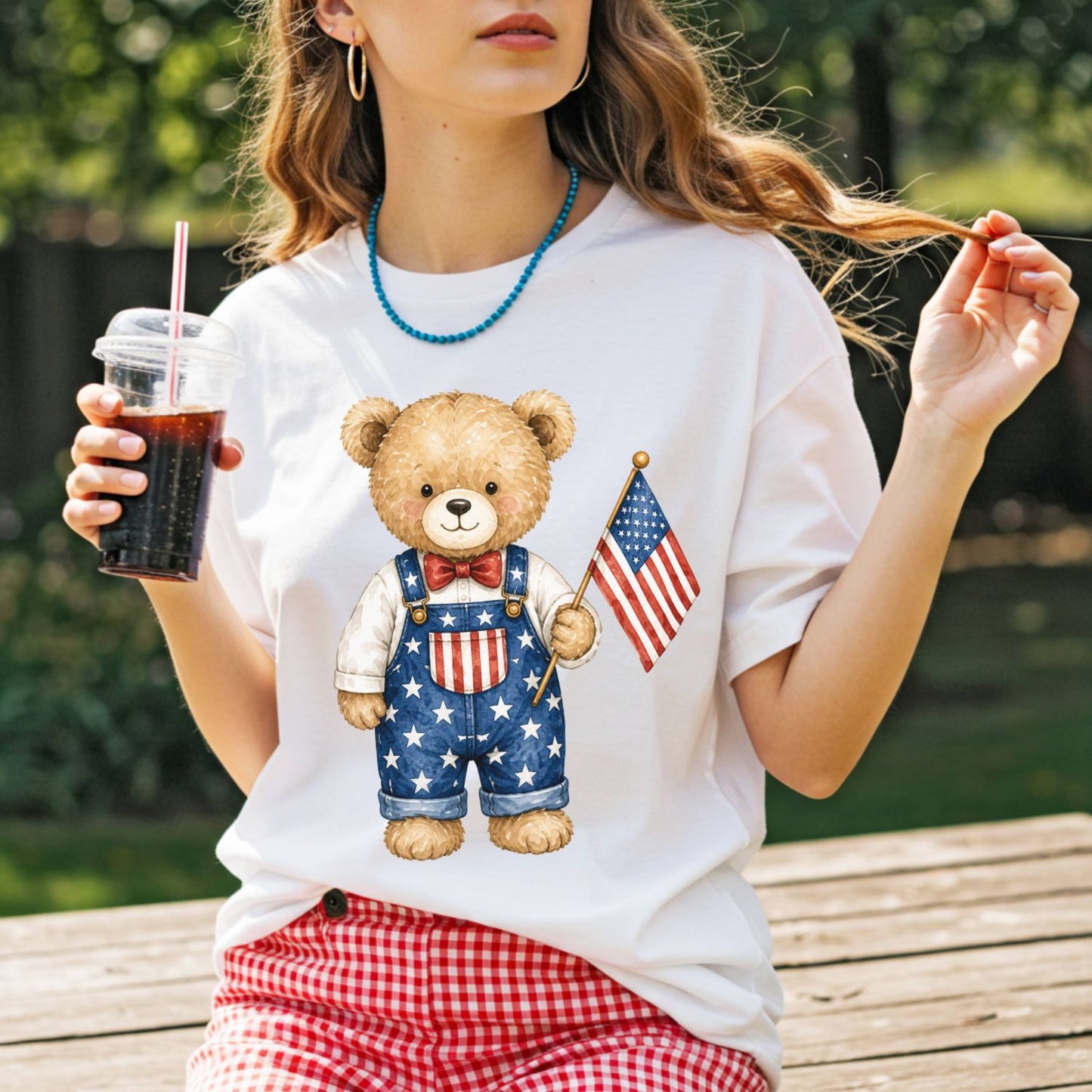 White t-shirt with a hand-drawn teddy bear in Americana overalls holding a US flag.