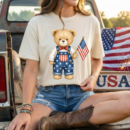 Relaxed-fit, garment-dyed t-shirt with a hand-drawn teddy bear in Americana overalls holding a US flag.