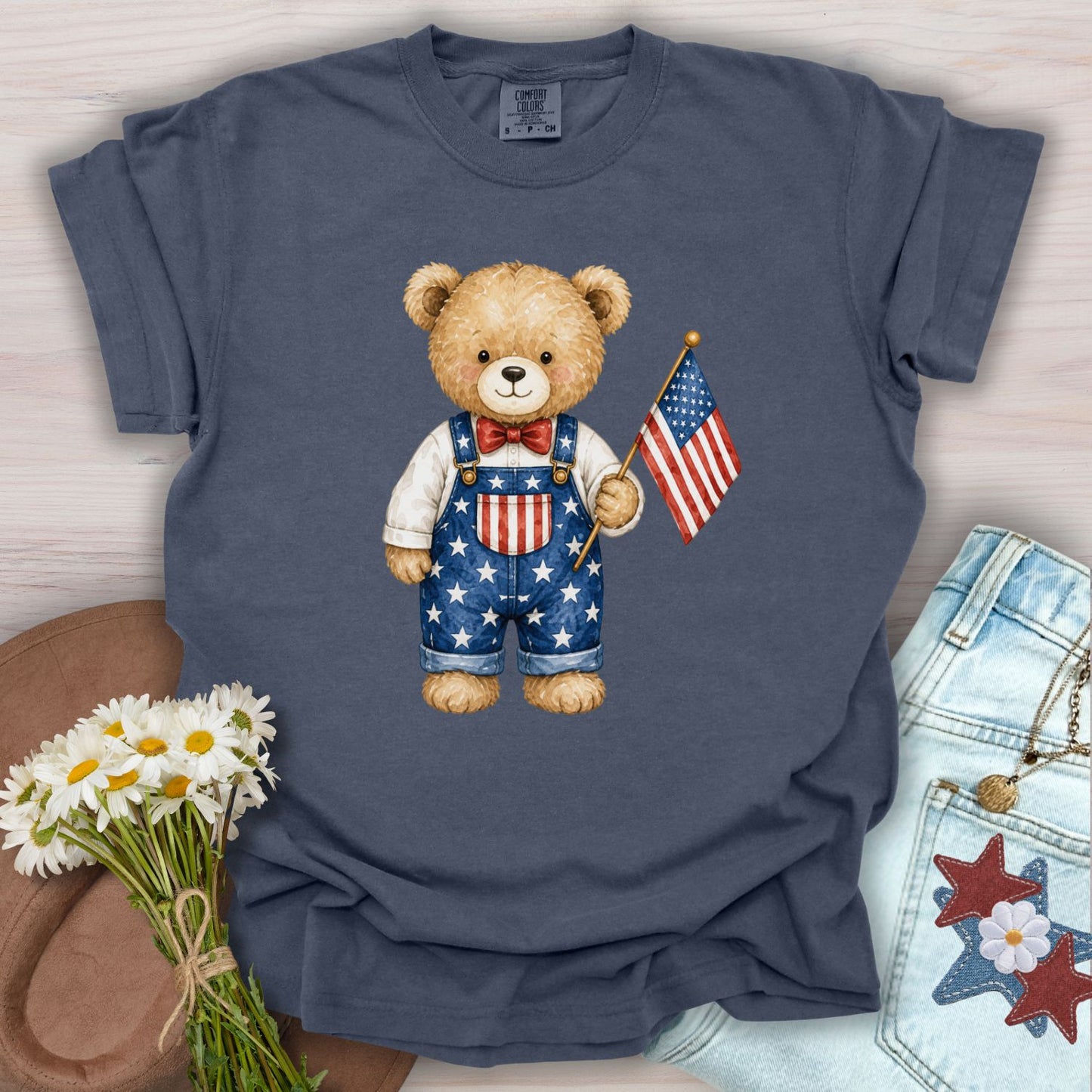 Denim S t-shirt with a hand-drawn teddy bear in Americana overalls holding a US flag.