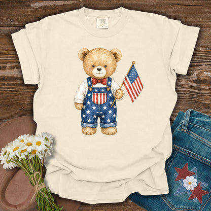 Ivory S t-shirt with a hand-drawn teddy bear in Americana overalls holding a US flag.