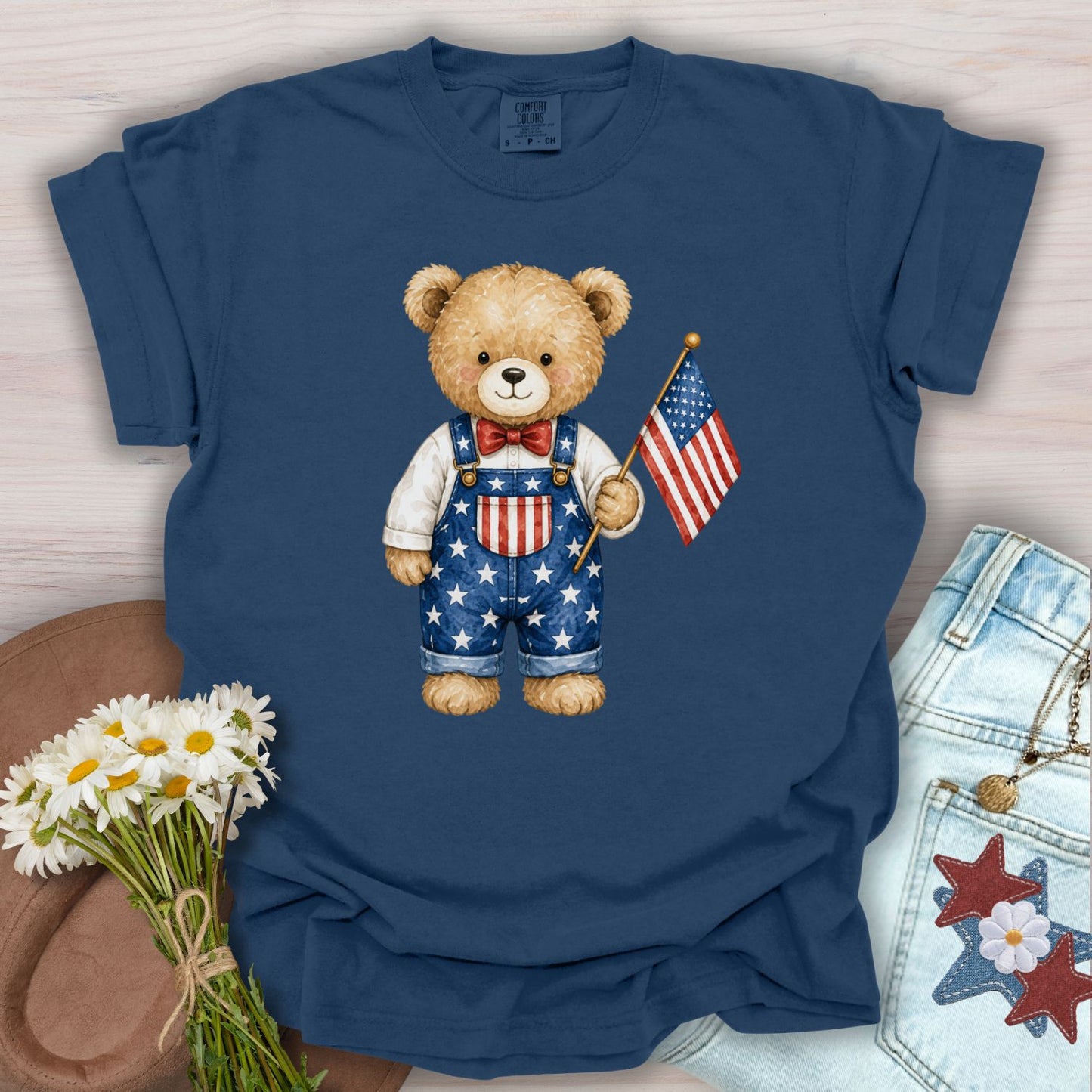 True Navy S t-shirt with a hand-drawn teddy bear in Americana overalls holding a US flag.