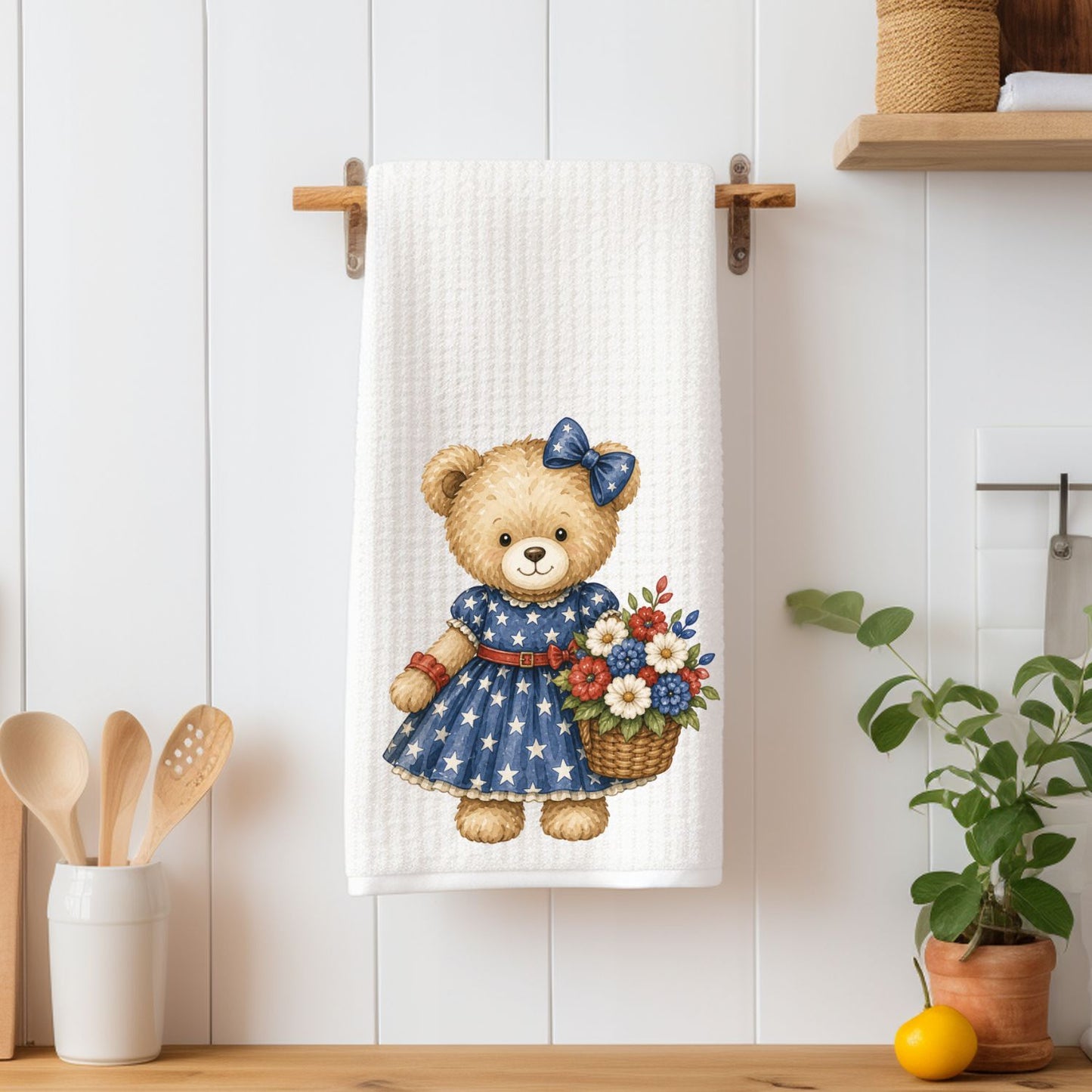 Patriotic teddy bear girl in a star-spangled dress holding a red, white, and blue floral basket on a white microfiber tea towel.