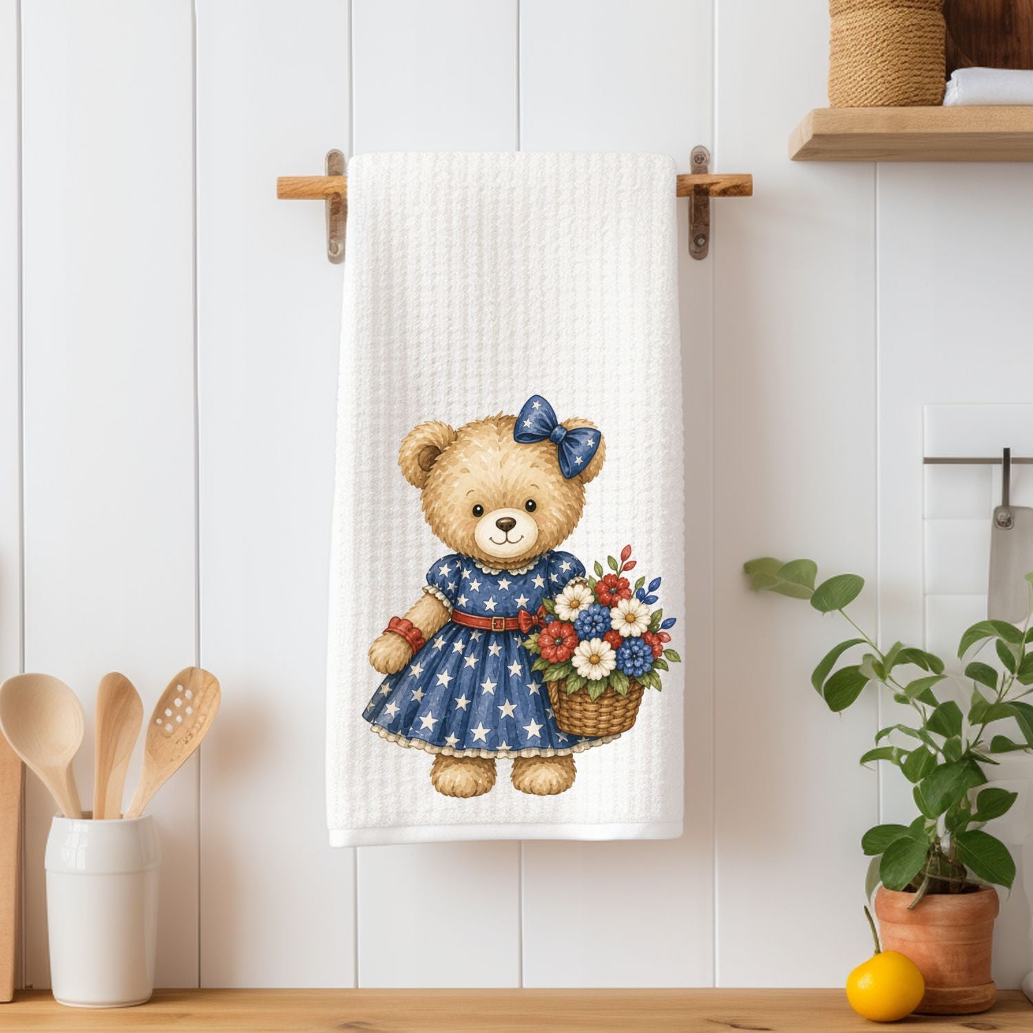 Patriotic teddy bear girl in a star-spangled dress holding a red, white, and blue floral basket on a white microfiber tea towel.