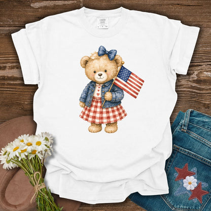 White S t-shirt with a hand-painted teddy bear in a gingham dress, denim jacket, and American flag.