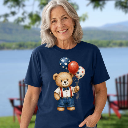 Woman in a navy blue t-shirt with a vintage teddy bear holding red, white, and blue star balloons.