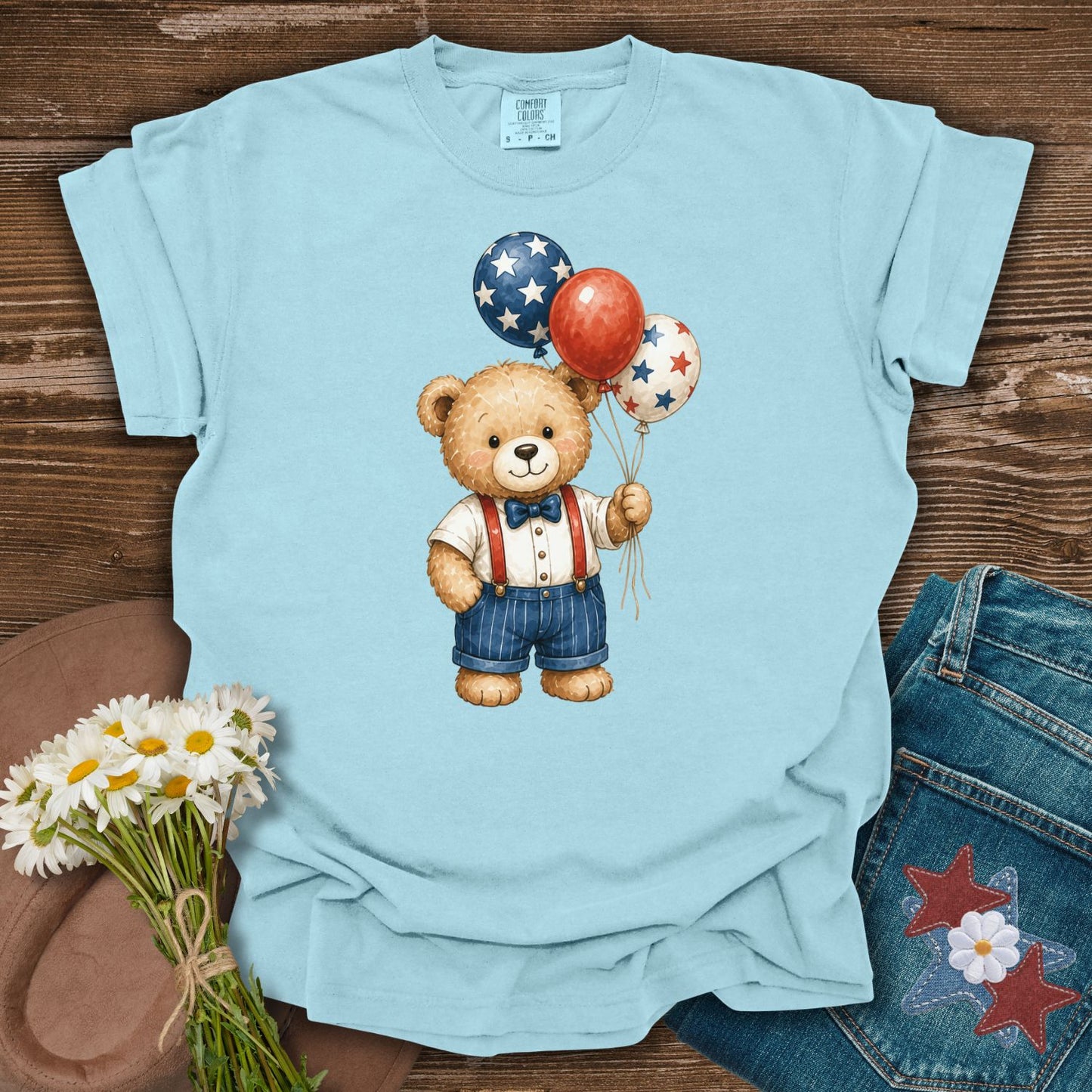 Chambray blue S-sized t-shirt with a vintage teddy bear holding red, white, and blue star balloons.