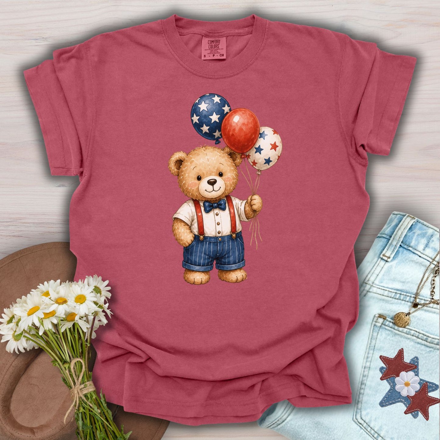 Crimson S tee with a vintage teddy bear holding red, white, and blue star balloons.