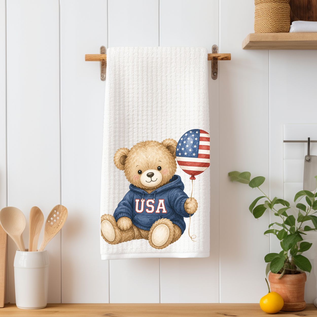 White waffle-weave tea towel with a watercolor teddy bear in a "USA" hoodie holding a flag balloon.