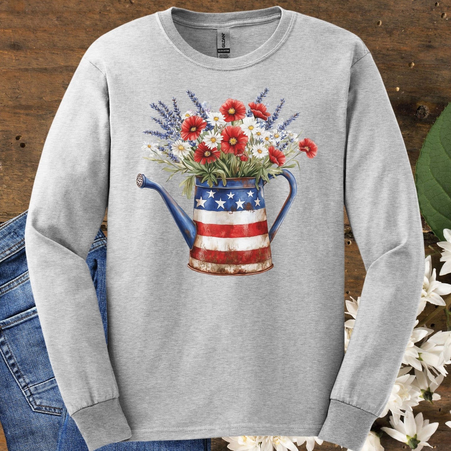 Ash gray long sleeve tee with a rustic patriotic watering can holding red, white, and blue wildflowers.