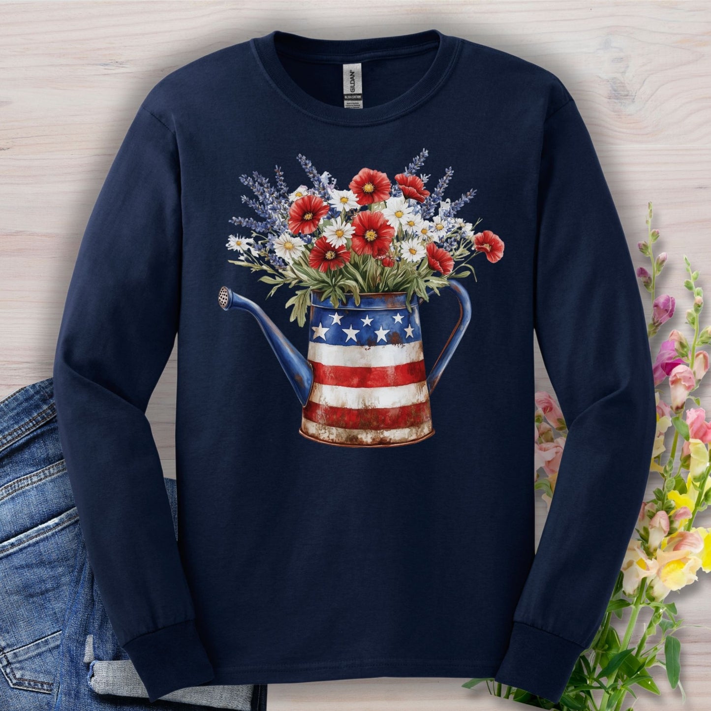 Navy long sleeve tee with a patriotic watering can holding red, white, and blue wildflowers.