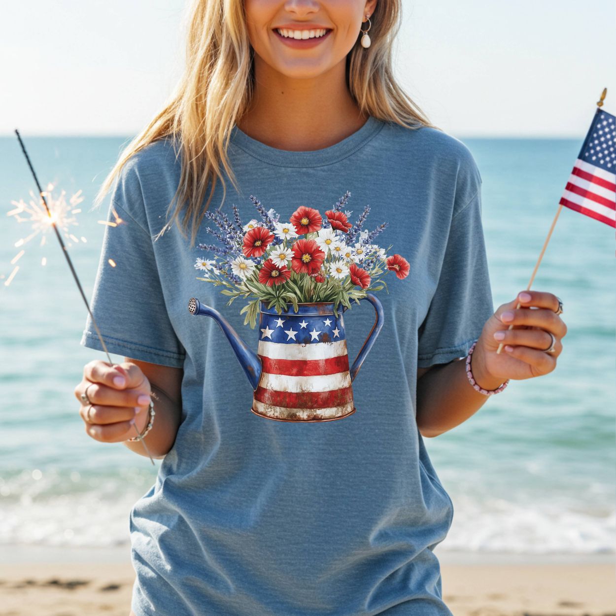 Woman in blue t-shirt with patriotic watering can overflowing with lavender, daisies, and red poppy-like flowers.