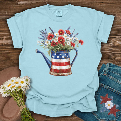 Chambray blue t-shirt with a rustic patriotic watering can overflowing with lavender, daisies, and red poppies.