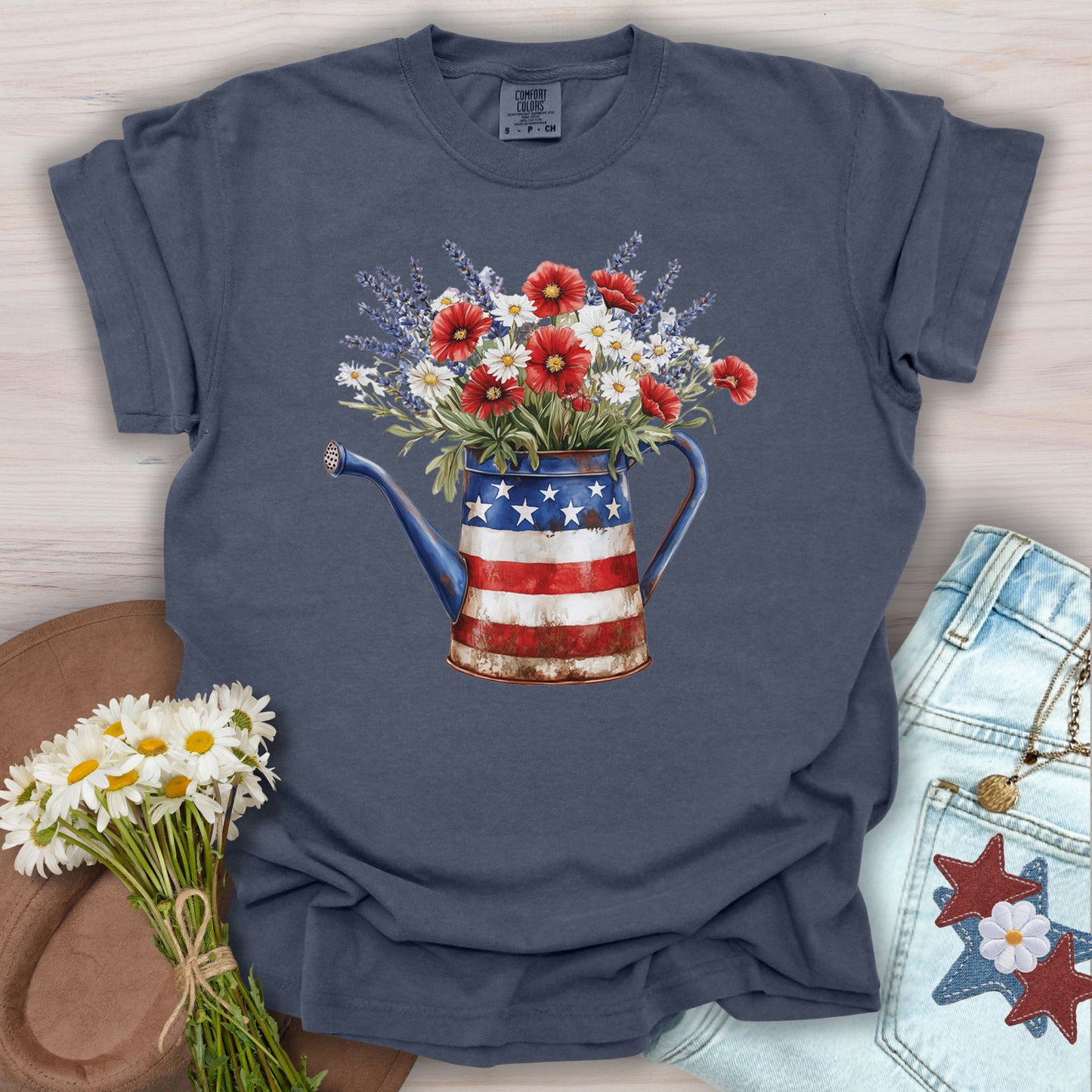 Denim S t-shirt with a rustic patriotic watering can overflowing with red poppies, white daisies, and lavender.