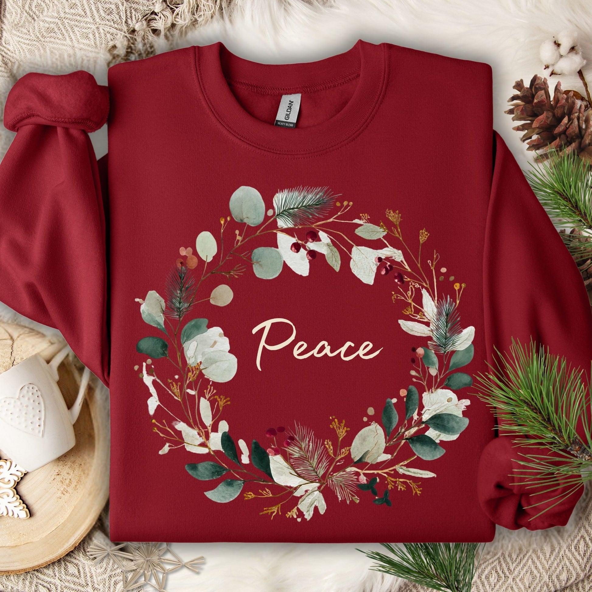 Cardinal Red Peace Christmas Wreath Sweatshirt with watercolor wreath and red berries, on a cozy background.