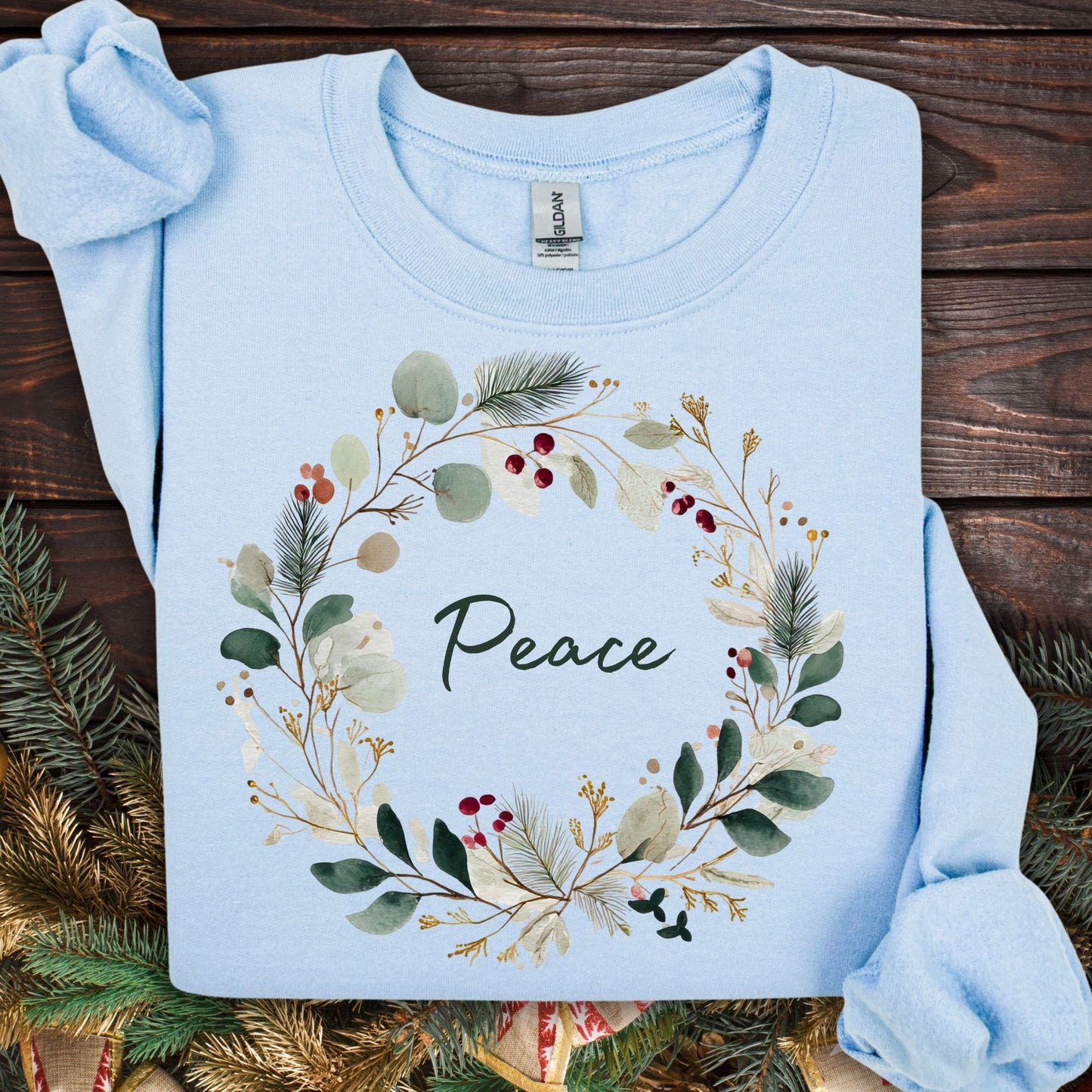 Light blue Gildan sweatshirt with watercolor Christmas wreath and "Peace" in green.