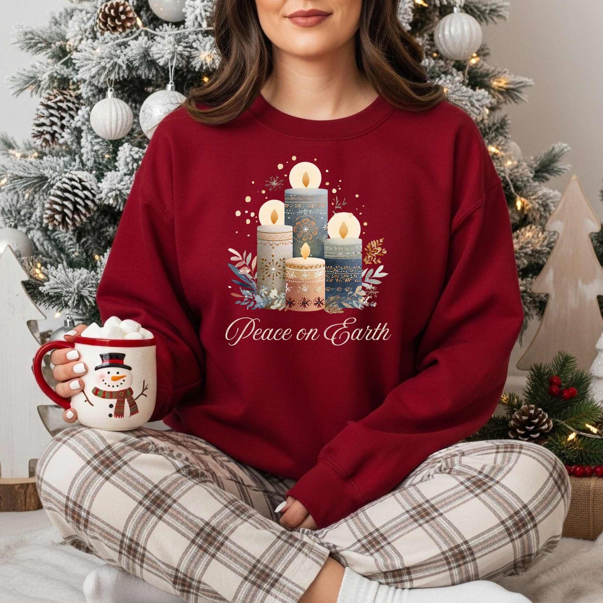 Woman in a red sweatshirt with Nordic-style advent candles and "Peace on Earth" text, holding a snowman mug.