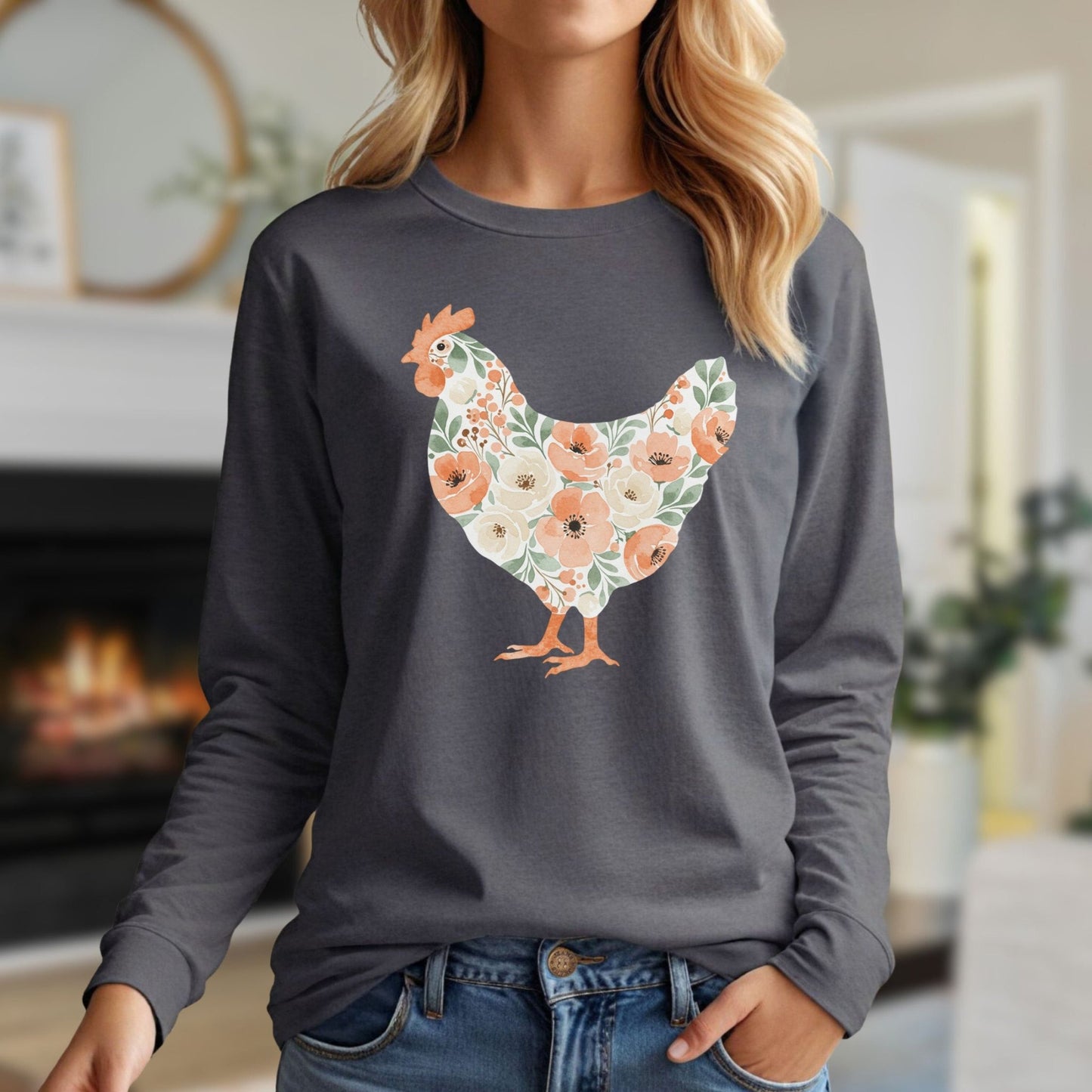 Woman in charcoal long sleeve tee with a watercolor floral hen design in peach, cream, and green.