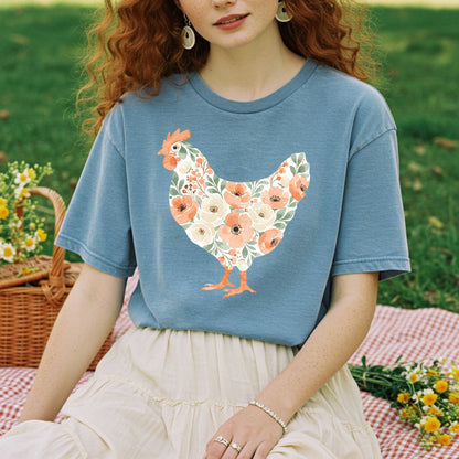 Woman in a blue t-shirt with a floral hen design, sitting on a red and white checkered blanket.