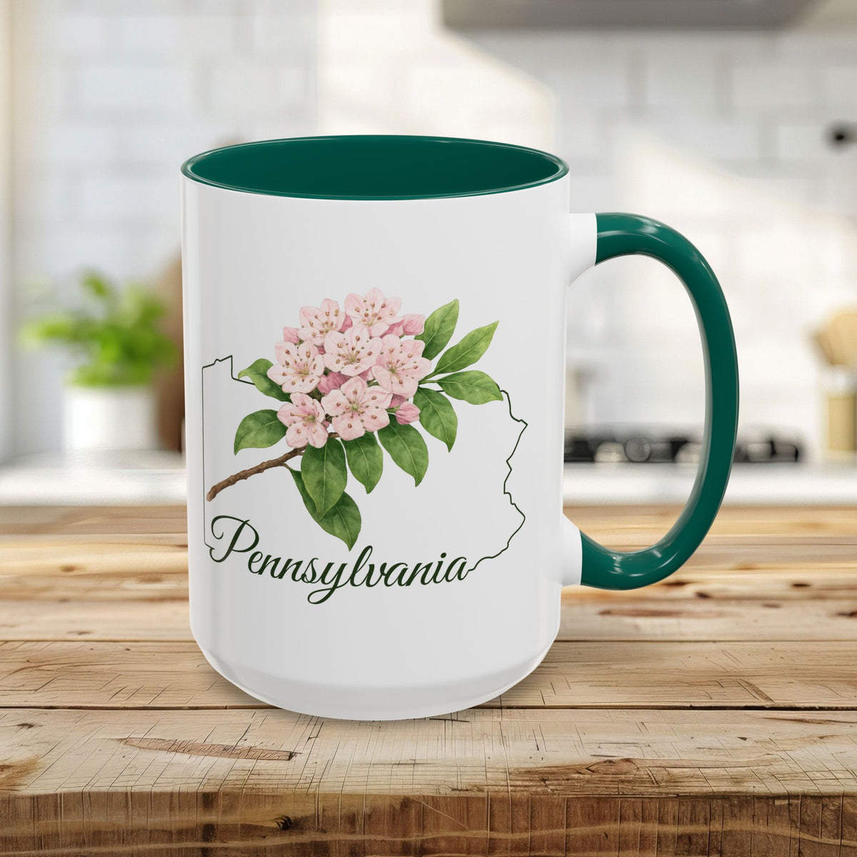 White 15oz ceramic mug with a green handle and interior, featuring a watercolor Mountain Laurel and Pennsylvania outline.