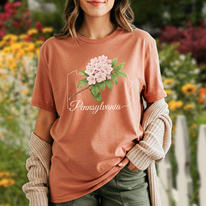 Garment-dyed rust t-shirt with a pink mountain laurel and Pennsylvania outline design.