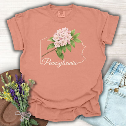 Terracotta garment-dyed t-shirt with a Pennsylvania outline and pink mountain laurel design.