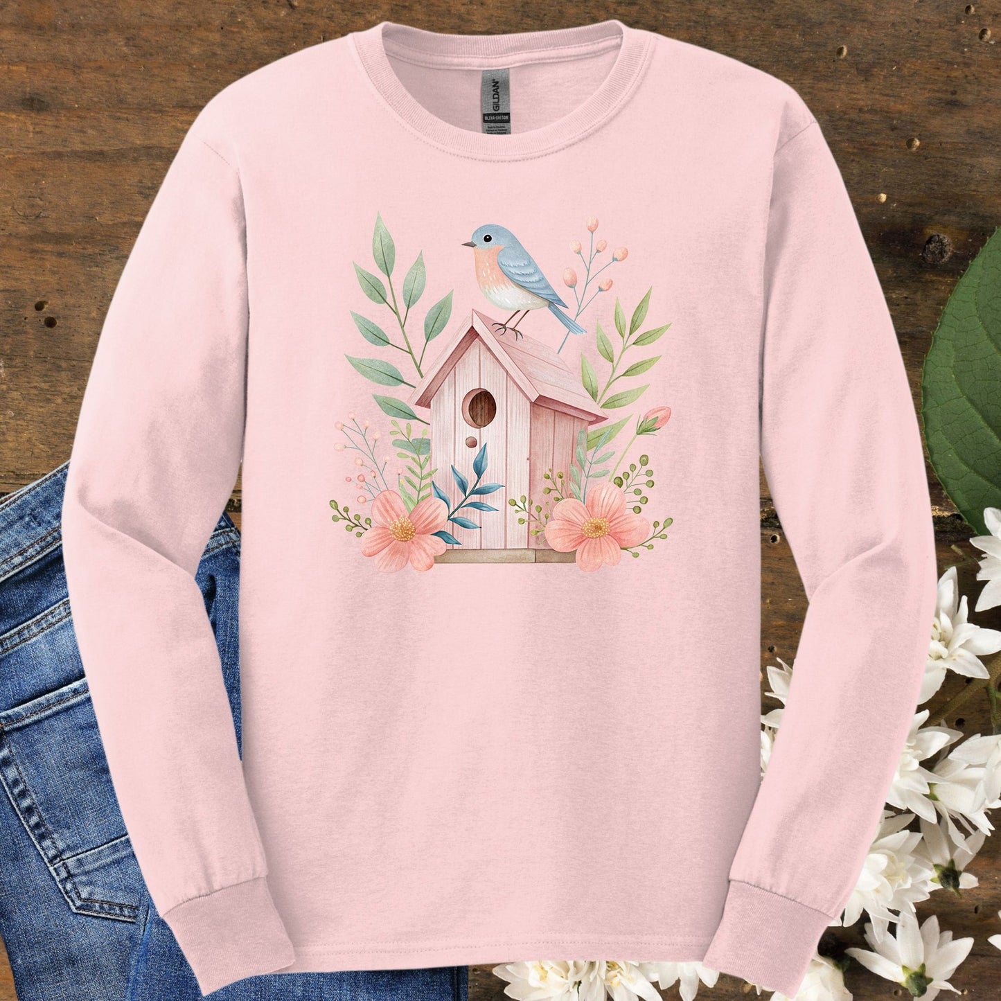 Light pink long sleeve tee with a watercolor birdhouse, blue bird, and floral design.
