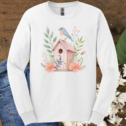 White long sleeve tee with a watercolor pink birdhouse, blue bird, and botanical design.