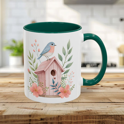 White 11oz ceramic mug with green interior/handle, featuring a watercolor bluebird on a pink birdhouse with peach blossoms.