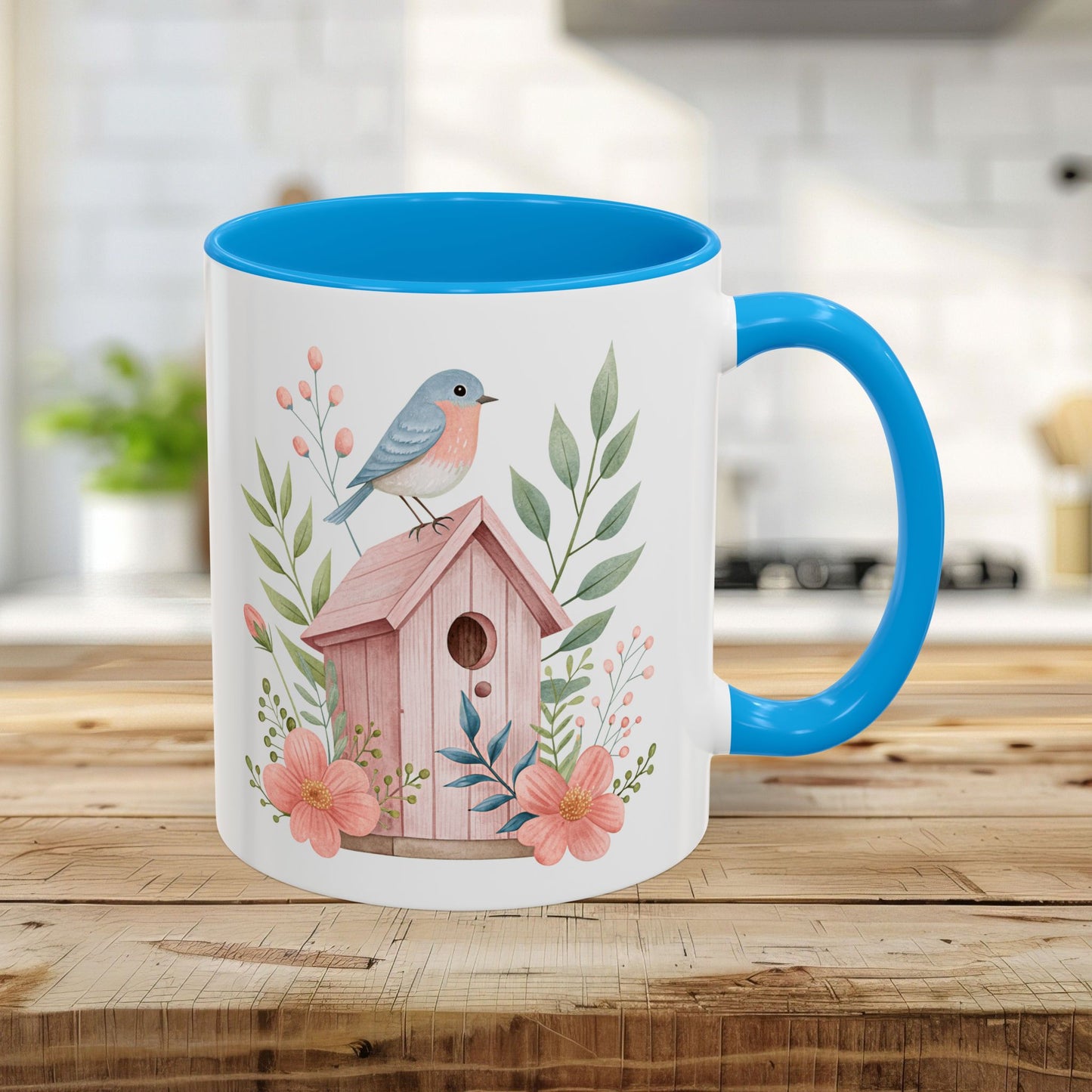 White ceramic 11oz mug with light blue interior/handle, featuring a watercolor pink birdhouse, bluebird, and peach blossoms.