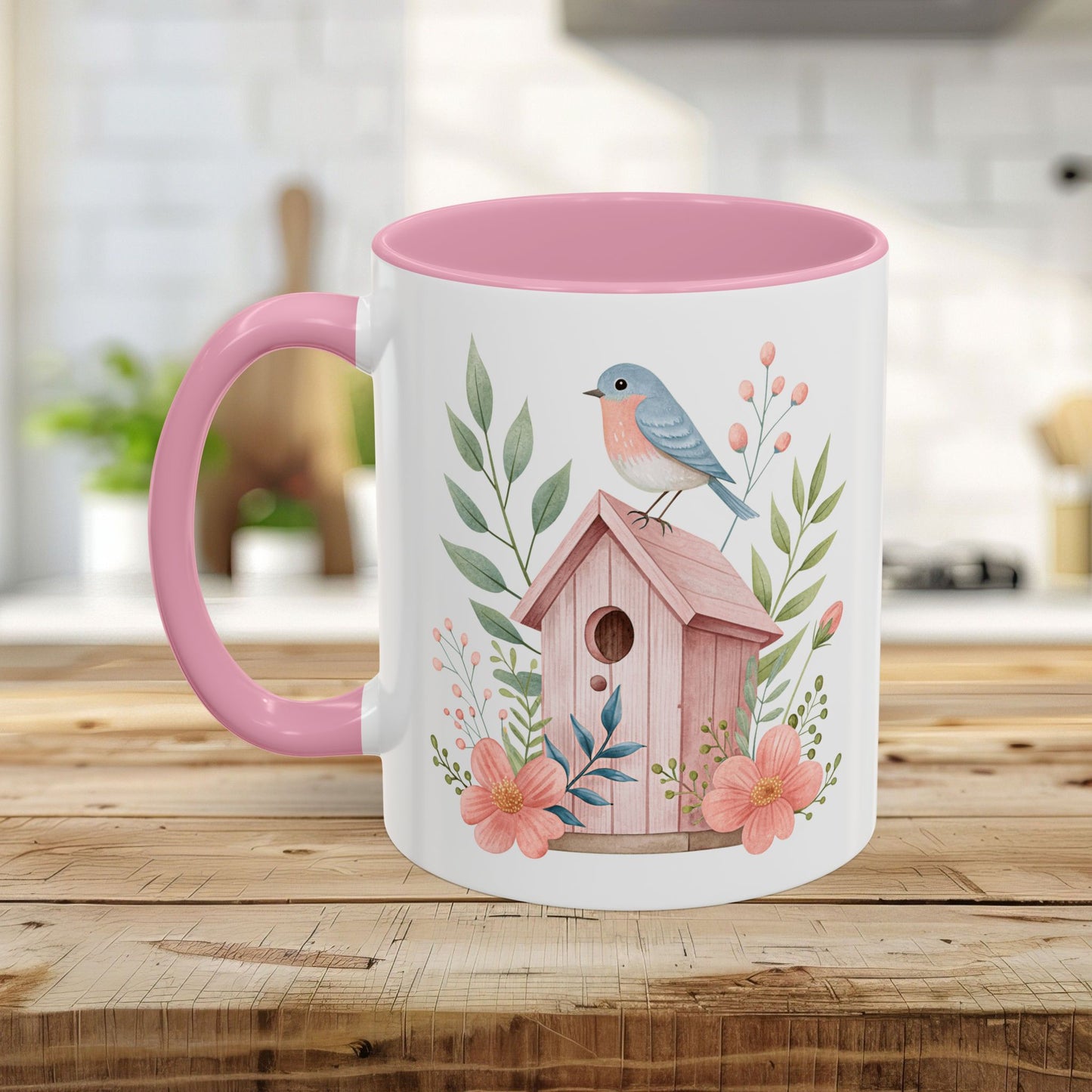 White ceramic mug with pink interior and handle, featuring a watercolor pink birdhouse, bluebird, and peach blossoms.