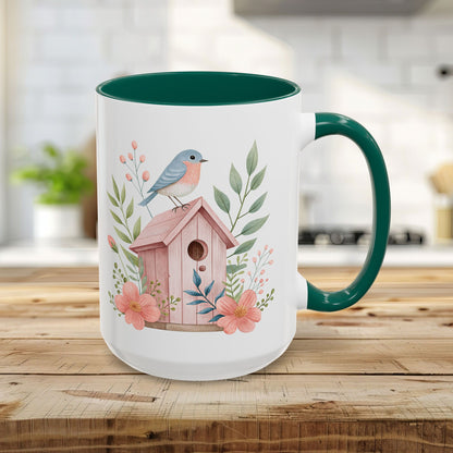 15oz white ceramic mug with green handle/interior, featuring a pink birdhouse, bluebird, and peach blossoms.