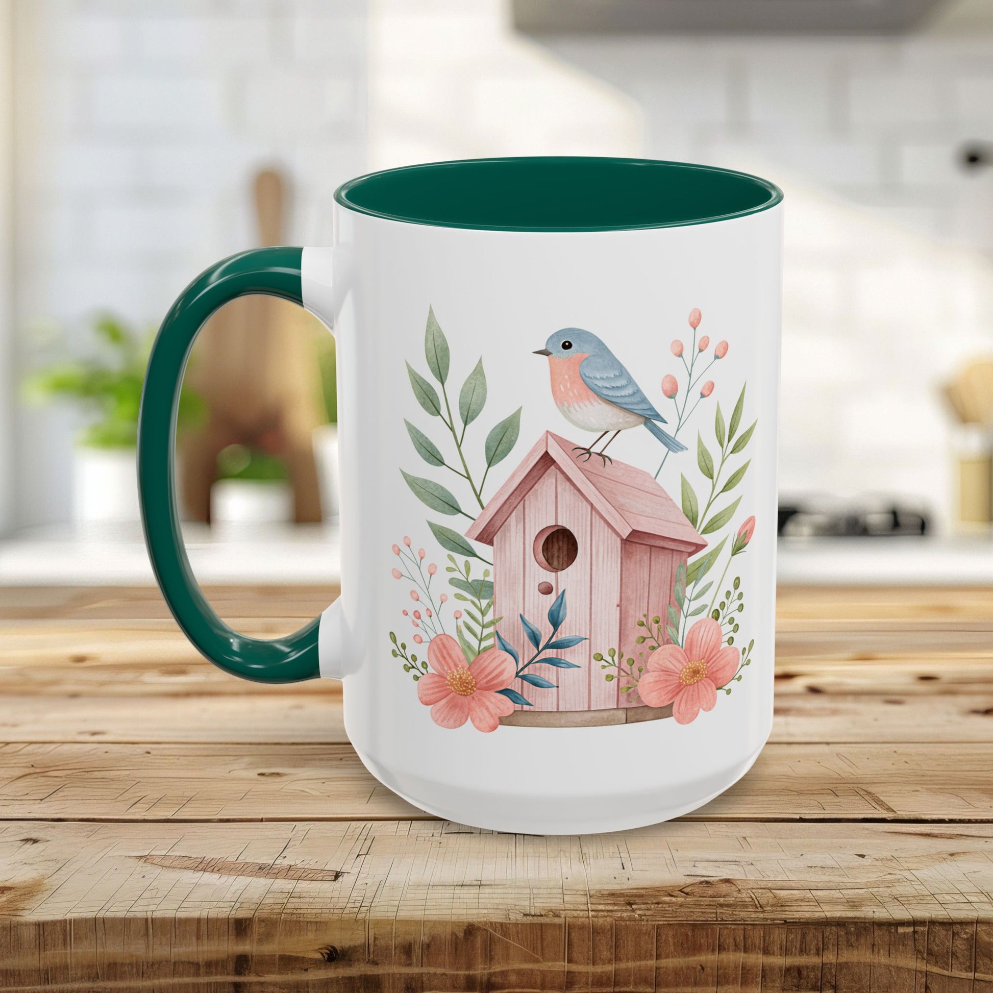 White ceramic mug with green handle and interior, featuring a watercolor pink birdhouse and bluebird design.