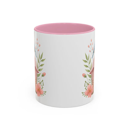 White ceramic mug with pink interior and a watercolor birdhouse, bluebird, and peach blossom design.
