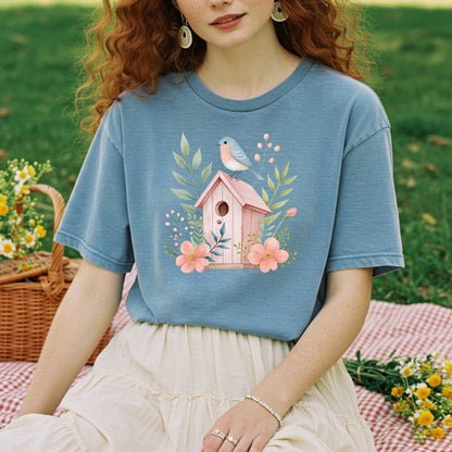 Relaxed-fit, garment-dyed blue t-shirt with a pink birdhouse, blue bird, and floral design.
