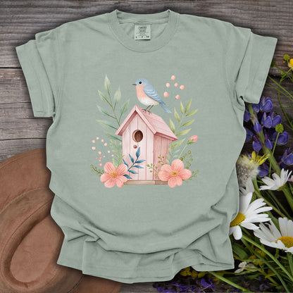 Bay S t-shirt with a watercolor pink birdhouse, blue bird, and floral design.