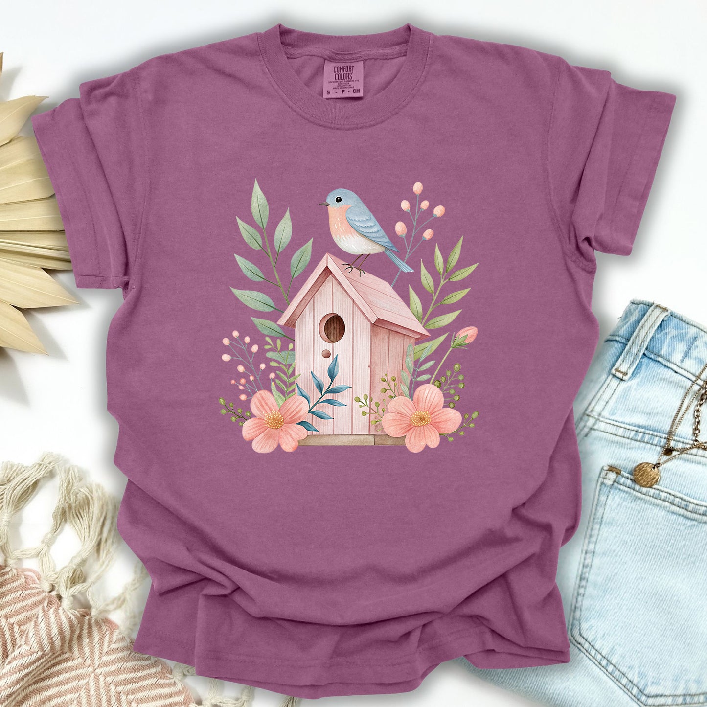 Berry S cotton t-shirt with a watercolor pink birdhouse, blue bird, and floral illustration.